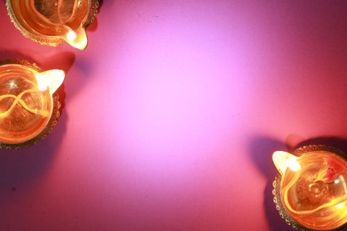 Diwali celebration. Diya lamps on color background, flat lay. Space for text