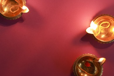 Photo of Diwali celebration. Diya lamps on color background, flat lay. Space for text