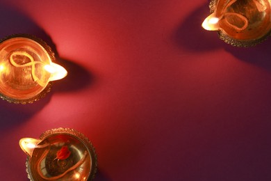 Diwali celebration. Diya lamps on color background, flat lay. Space for text