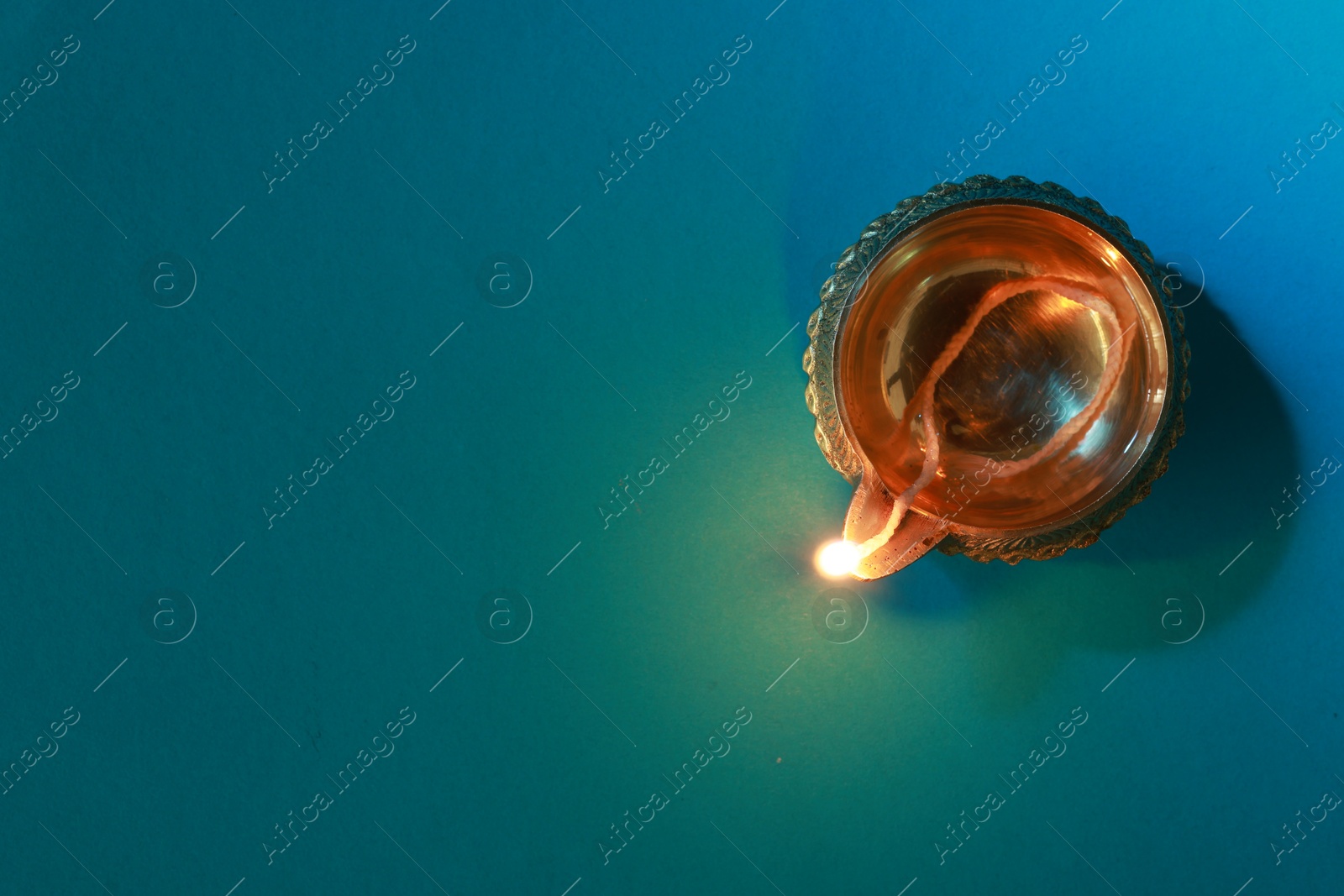 Photo of Diwali celebration. Diya lamp on teal background, top view. Space for text