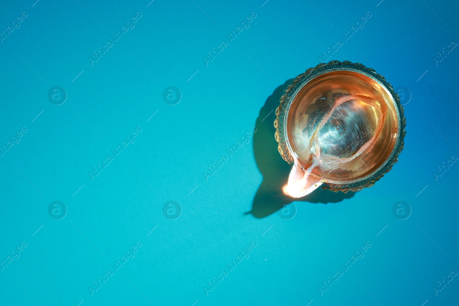 Photo of Diwali celebration. Diya lamp on teal background, top view. Space for text