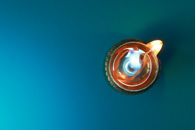 Photo of Diwali celebration. Diya lamp on teal background, top view. Space for text