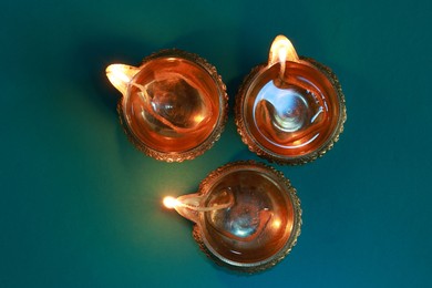 Diwali celebration. Diya lamps on teal background, flat lay