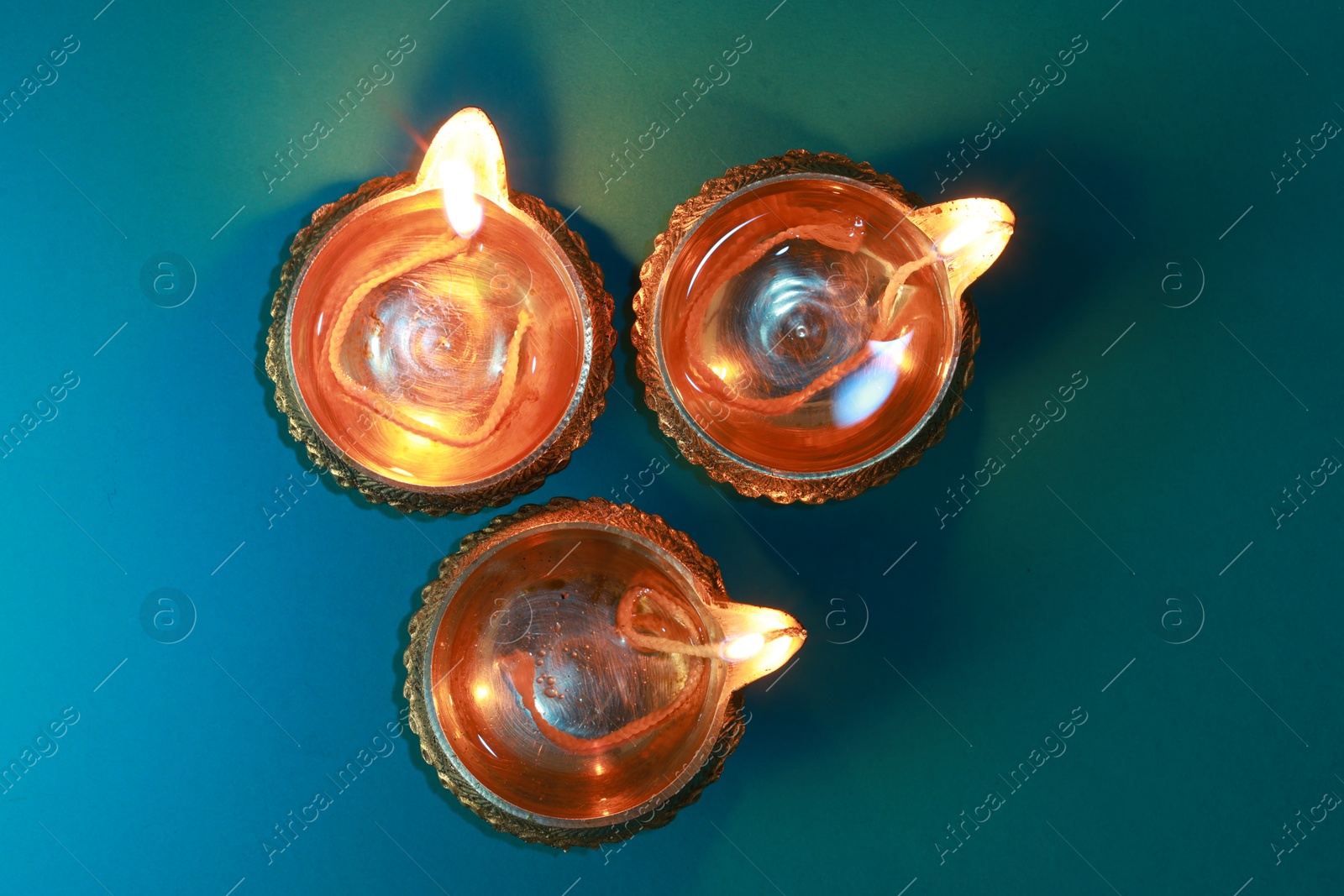 Photo of Diwali celebration. Diya lamps on teal background, flat lay