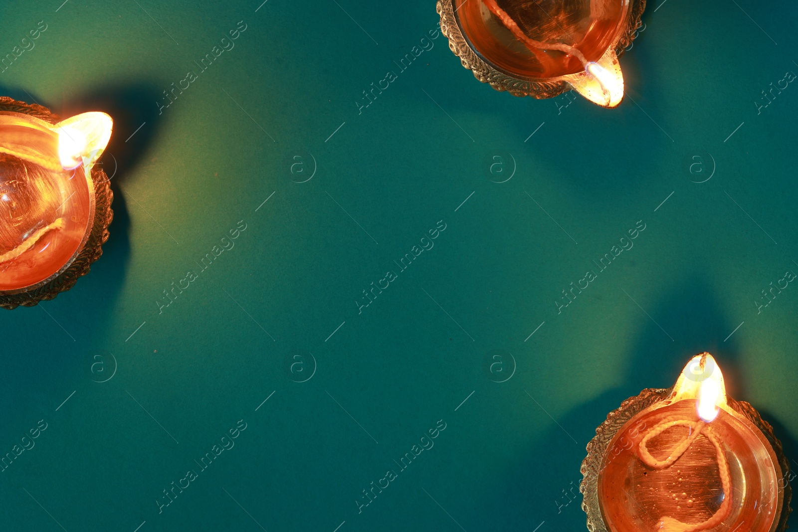 Photo of Diwali celebration. Diya lamps on teal background, flat lay. Space for text