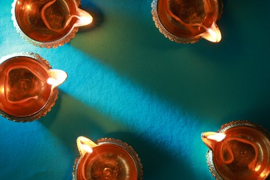 Photo of Diwali celebration. Diya lamps on teal background, flat lay. Space for text