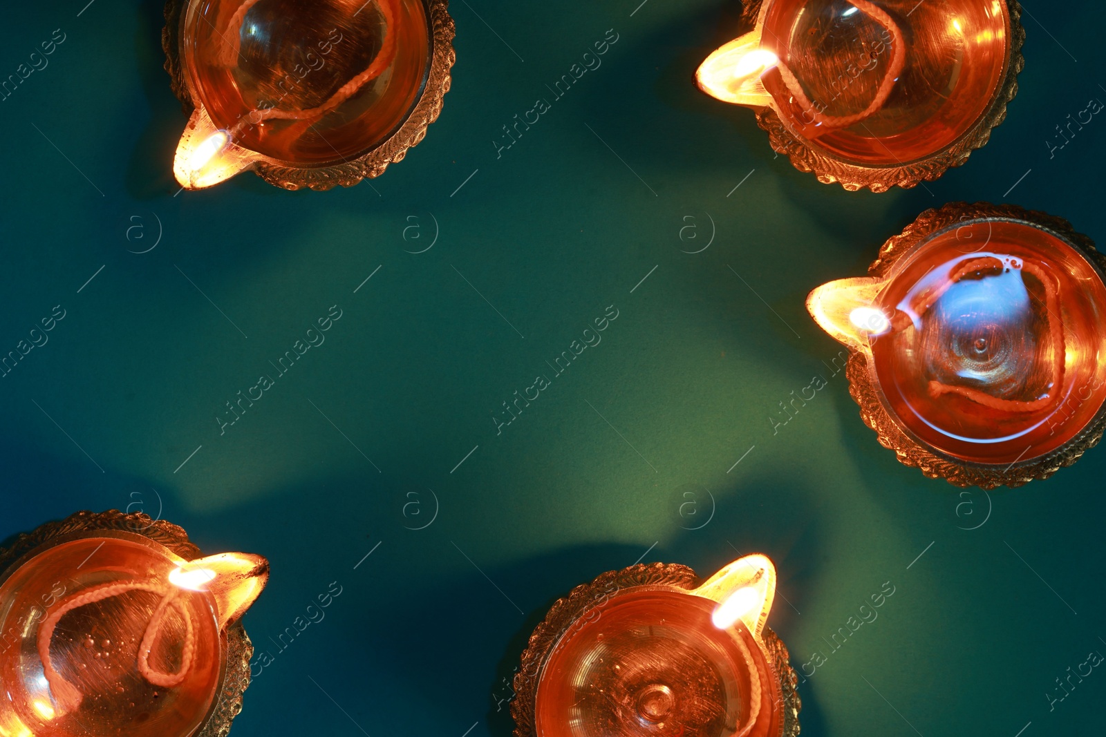 Photo of Diwali celebration. Diya lamps on teal background, flat lay. Space for text