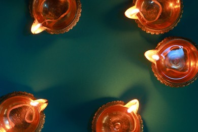 Diwali celebration. Diya lamps on teal background, flat lay. Space for text