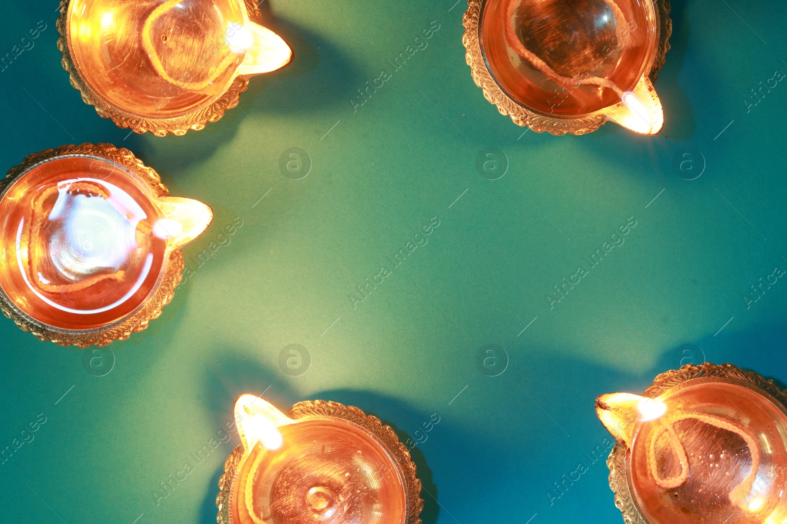 Photo of Diwali celebration. Diya lamps on teal background, flat lay. Space for text