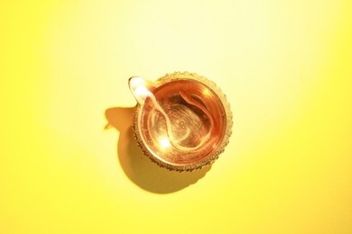 Photo of Diwali celebration. Diya lamp on yellow background, top view