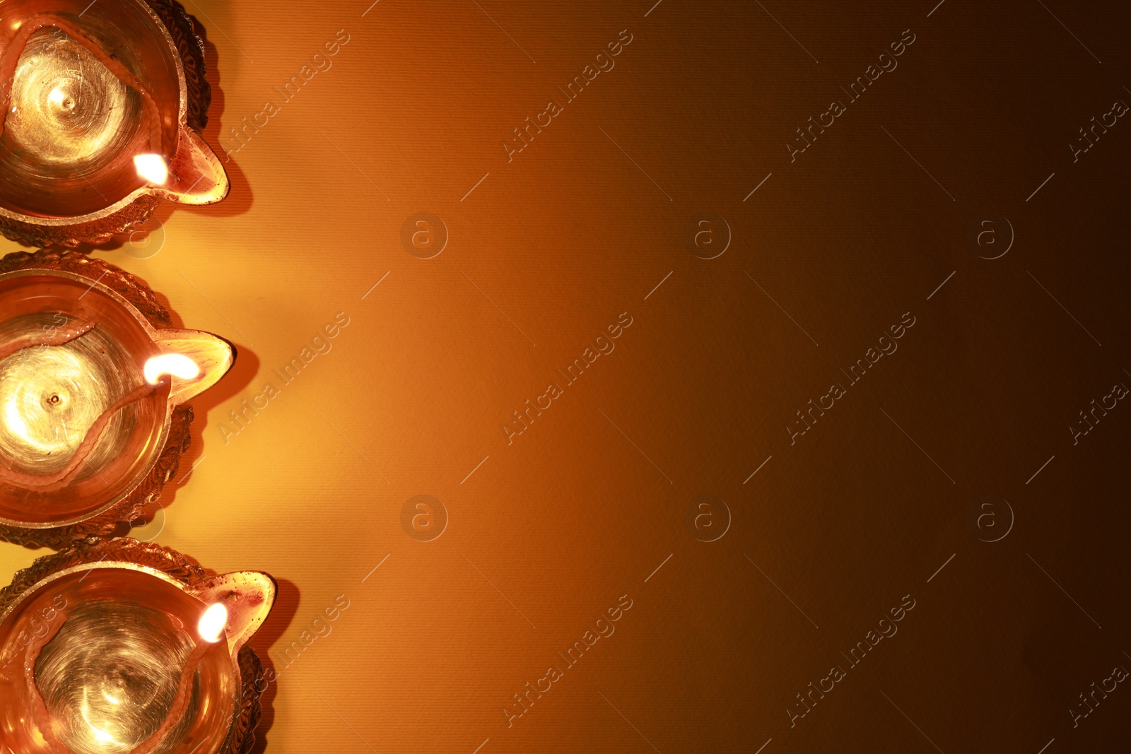 Photo of Diwali celebration. Diya lamps on orange background, flat lay. Space for text