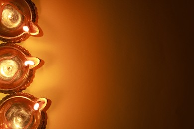 Diwali celebration. Diya lamps on orange background, flat lay. Space for text