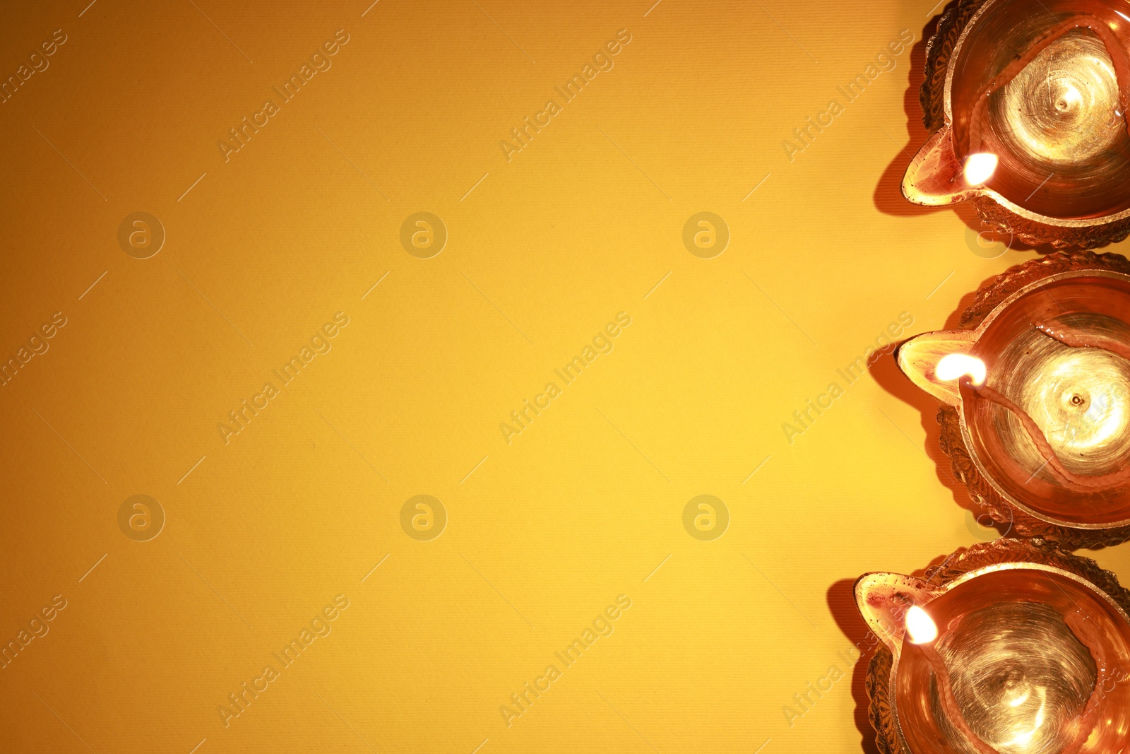 Photo of Diwali celebration. Diya lamps on orange background, flat lay. Space for text