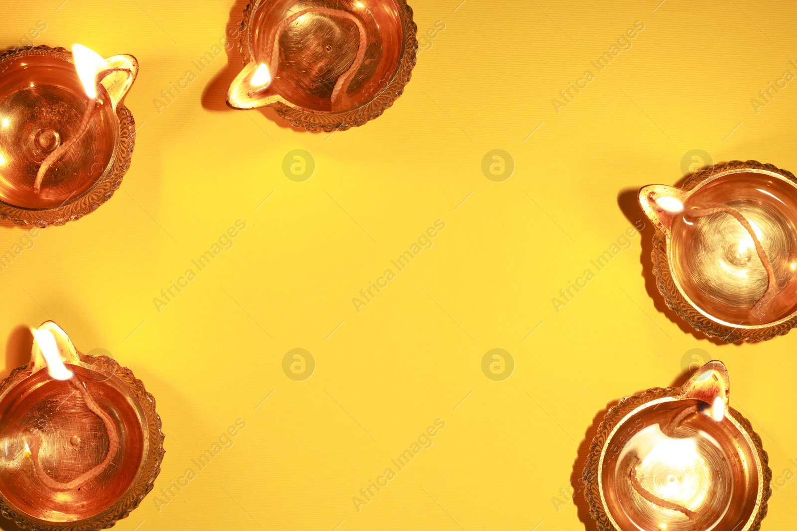 Photo of Diwali celebration. Diya lamps on orange background, flat lay. Space for text