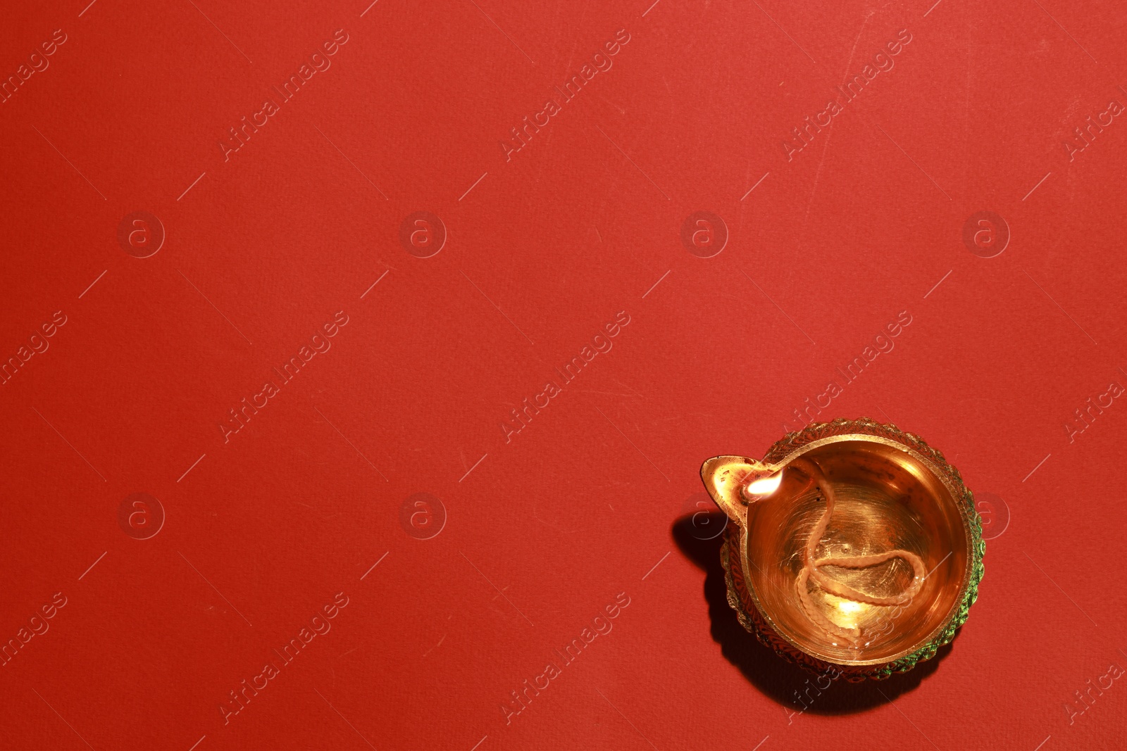 Photo of Diwali celebration. Diya lamp on red background, top view. Space for text