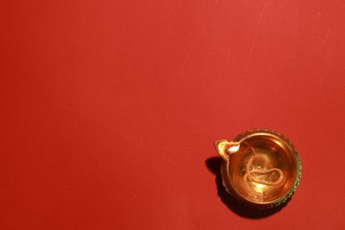 Photo of Diwali celebration. Diya lamp on red background, top view. Space for text