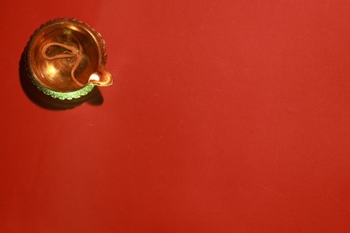 Photo of Diwali celebration. Diya lamp on red background, top view. Space for text