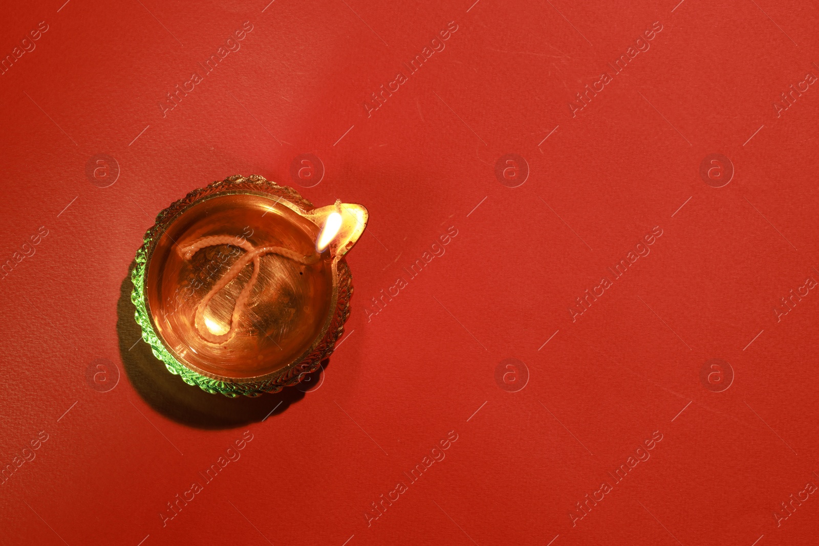 Photo of Diwali celebration. Diya lamp on red background, top view. Space for text