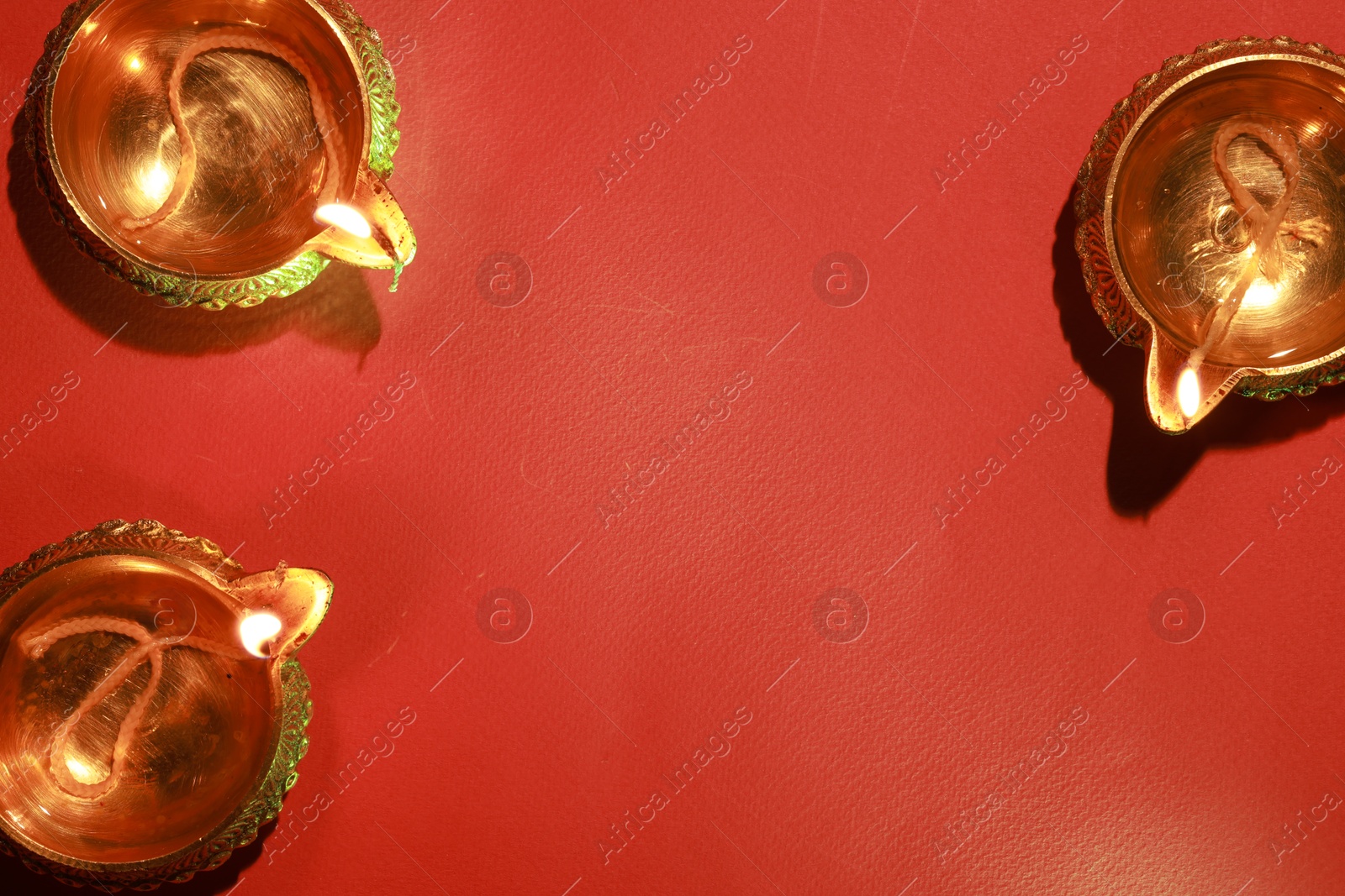 Photo of Diwali celebration. Diya lamps on red background, flat lay. Space for text