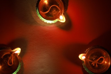 Diwali celebration. Diya lamps on red background, flat lay. Space for text