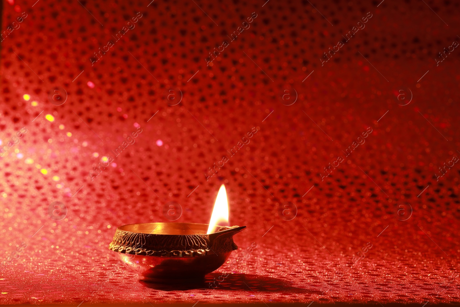 Photo of Diwali celebration. Diya lamp on red background. Space for text