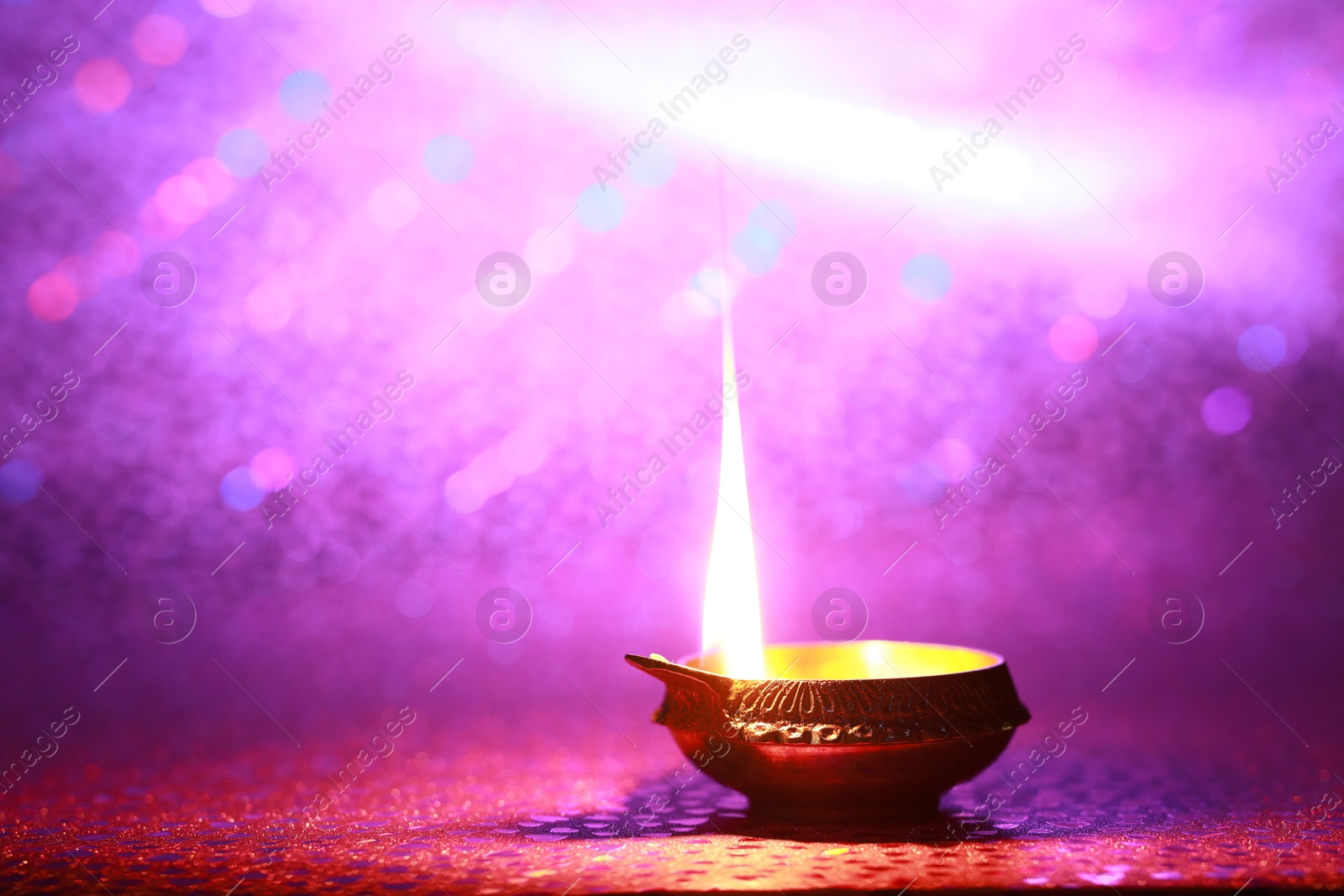 Photo of Diwali celebration. Diya lamp on purple background. Space for text