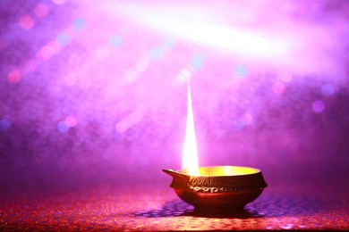 Photo of Diwali celebration. Diya lamp on purple background. Space for text