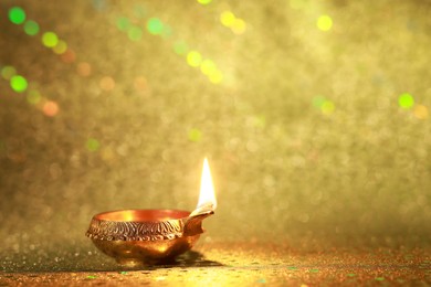 Photo of Diwali celebration. Diya lamp on golden background. Space for text