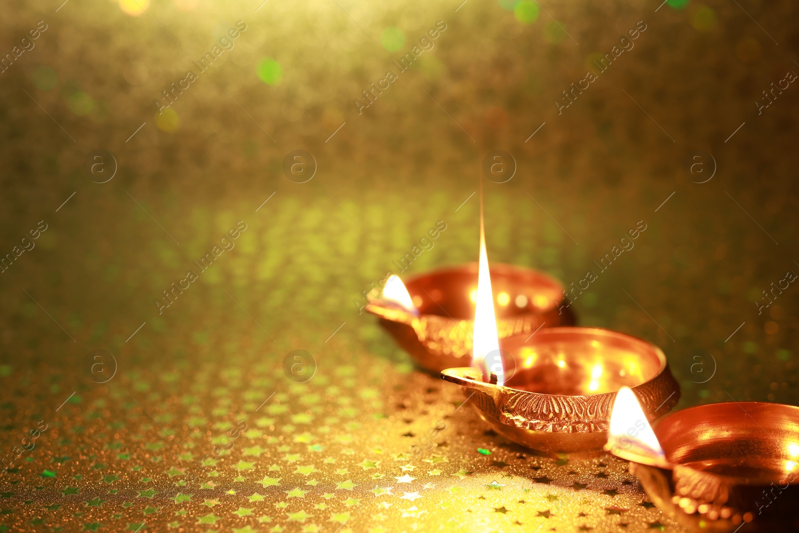 Photo of Diwali celebration. Diya lamps on golden background. Space for text