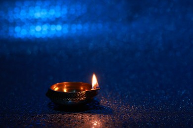 Diwali celebration. Diya lamp on blue background. Space for text