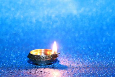 Photo of Diwali celebration. Diya lamp on blue background. Space for text