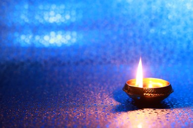 Diwali celebration. Diya lamp on blue background. Space for text