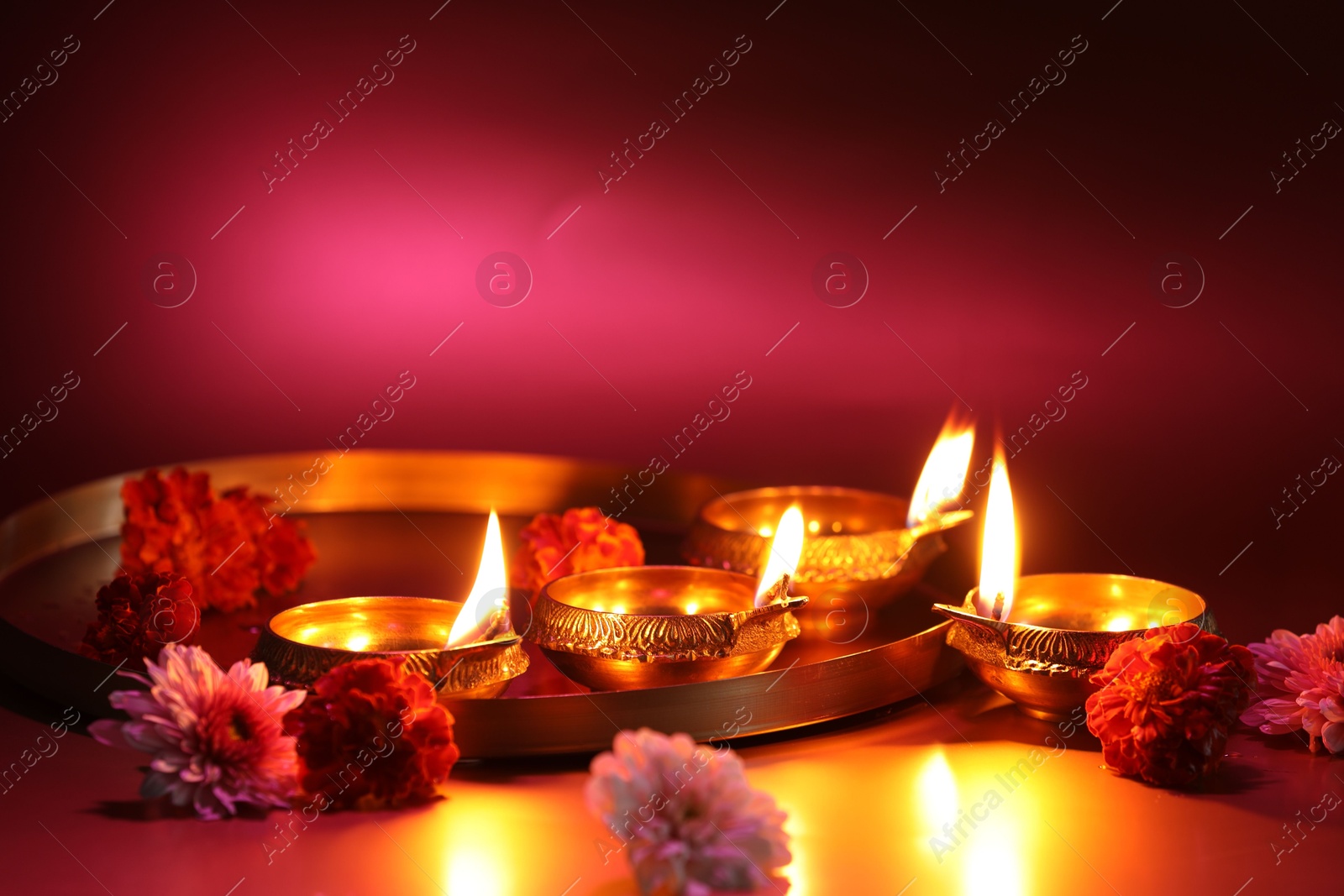 Photo of Diwali celebration. Diya lamps and beautiful flowers on color background, closeup