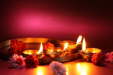 Photo of Diwali celebration. Diya lamps and beautiful flowers on color background, closeup