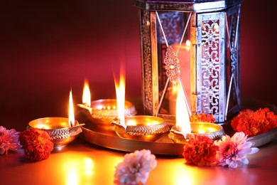 Photo of Diwali celebration. Diya lamps and beautiful flowers on color background, closeup