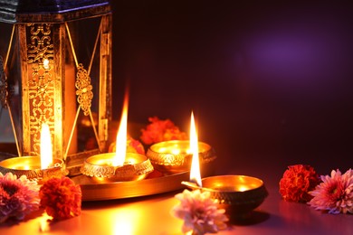 Photo of Diwali celebration. Diya lamps and beautiful flowers on color background, closeup