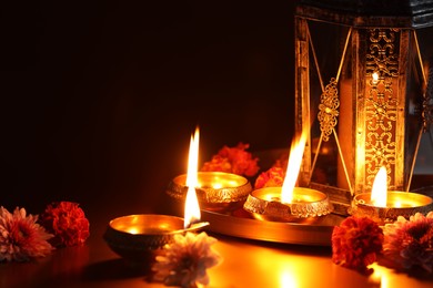 Photo of Diwali celebration. Diya lamps and beautiful flowers on color background, closeup