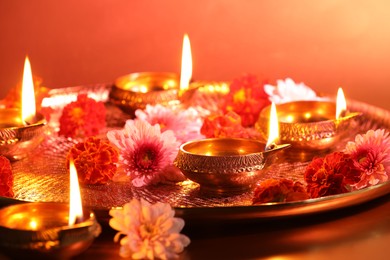 Photo of Diwali celebration. Diya lamps and beautiful flowers on color background, closeup