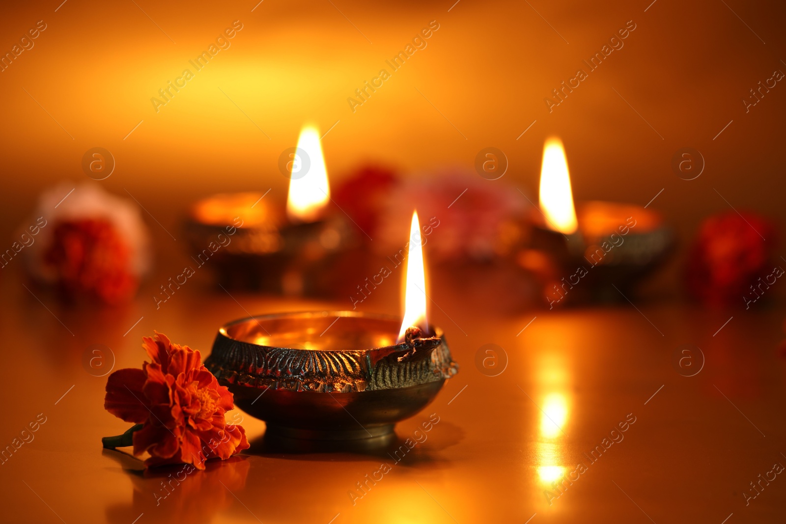 Photo of Diwali celebration. Diya lamps and beautiful flowers on golden background, closeup