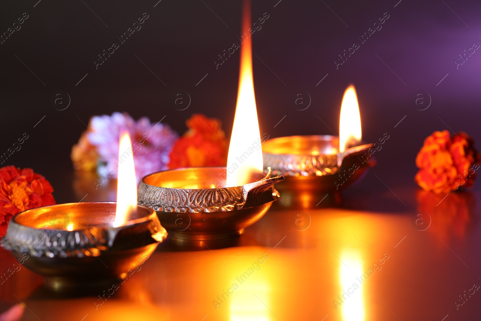 Photo of Diwali celebration. Diya lamps and beautiful flowers on color background, closeup