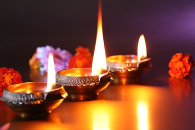 Photo of Diwali celebration. Diya lamps and beautiful flowers on color background, closeup