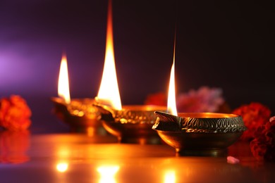 Photo of Diwali celebration. Diya lamps and beautiful flowers on color background, closeup