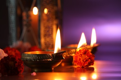 Diwali celebration. Diya lamps and beautiful flowers on color background, closeup