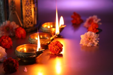 Photo of Diwali celebration. Diya lamps and beautiful flowers on color background, closeup