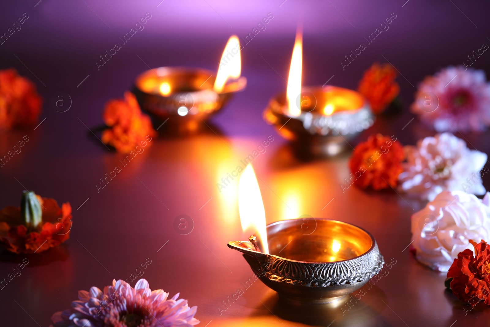 Photo of Diwali celebration. Diya lamps and beautiful flowers on color background, closeup