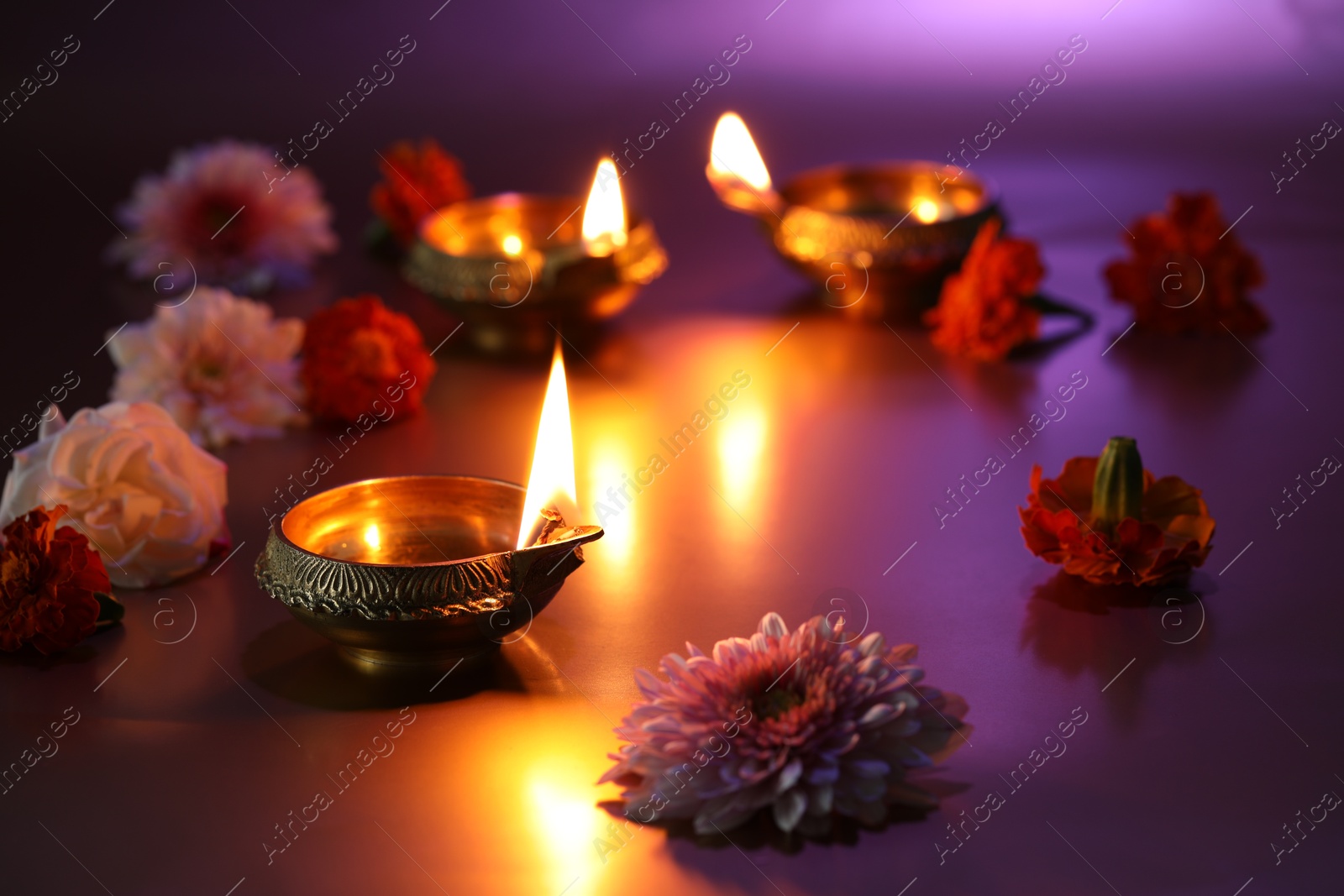 Photo of Diwali celebration. Diya lamps and beautiful flowers on color background, closeup