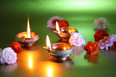 Photo of Diwali celebration. Diya lamps and beautiful flowers on green background