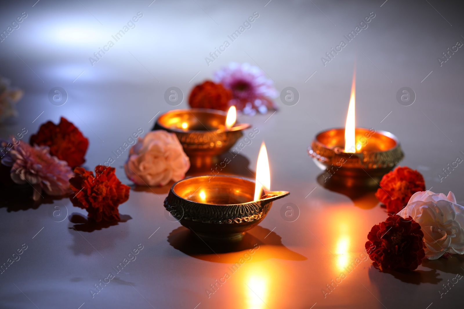 Photo of Diwali celebration. Diya lamps and beautiful flowers on color background, closeup