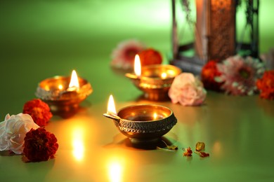 Diwali celebration. Diya lamps and beautiful flowers on green background