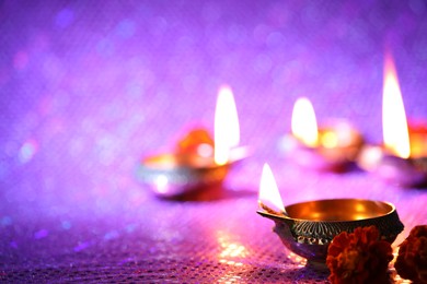 Photo of Diwali celebration. Diya lamps and beautiful flowers on color background, closeup. Space for text